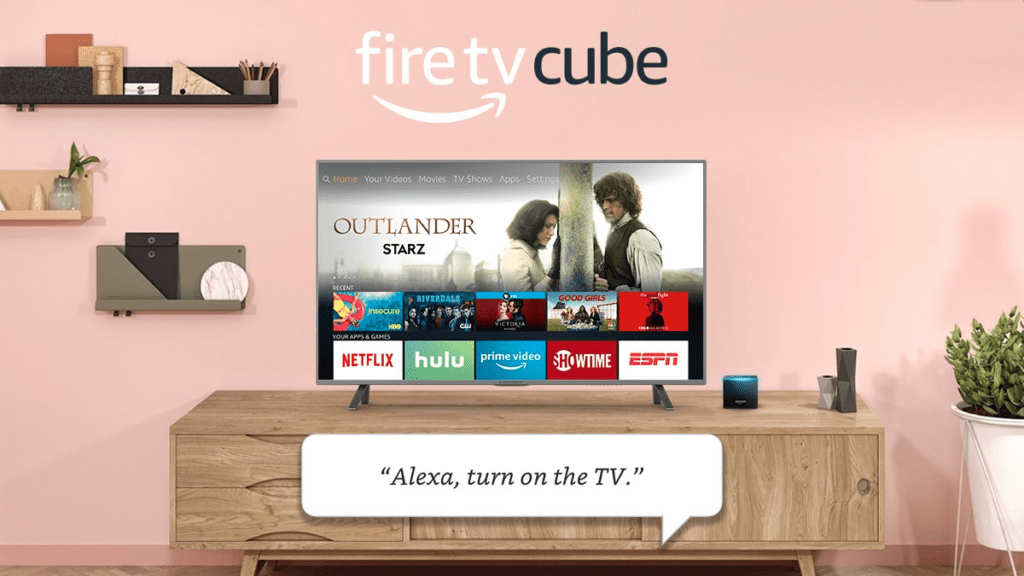 A flat-screen TV on top of a rack with the Fire TV Cube, Outlander showing on screen with a tile menu of various apps, and a voice command for Alexa to turn on the TV